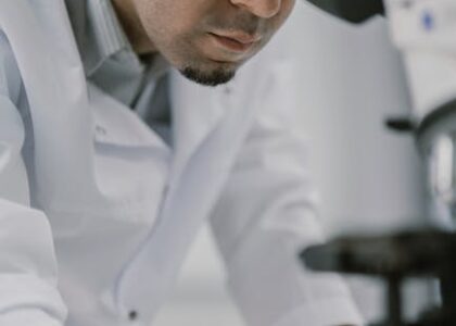 Scientist in laboratory observing a sample through a microscope with focus and precision.