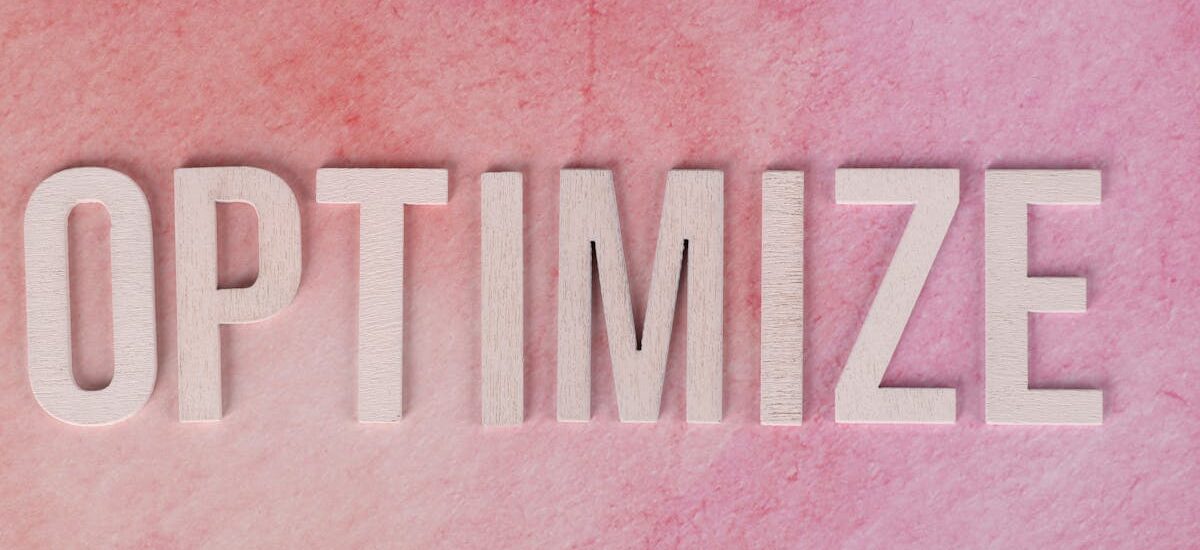 Creative display of the word 'OPTIMIZE' on a pink textured surface.
