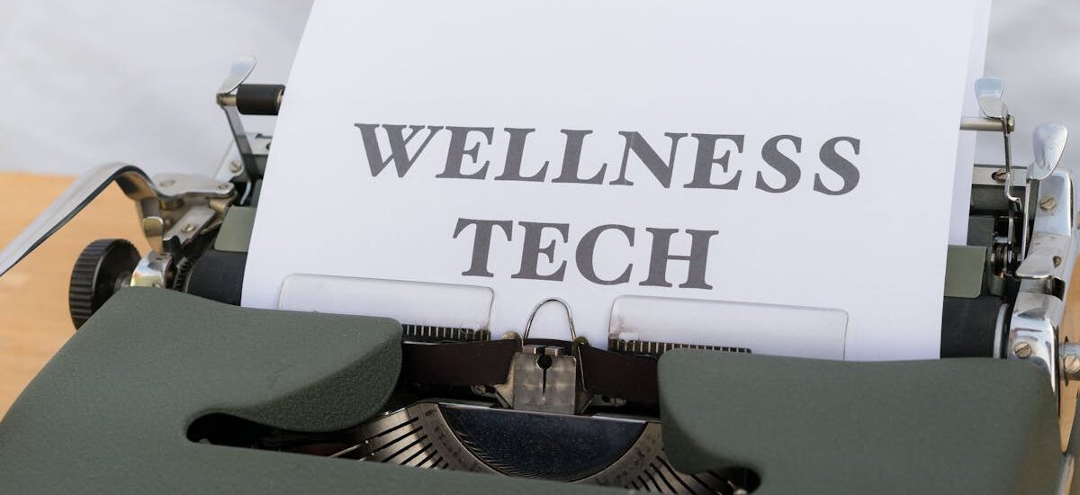 A close-up of a vintage typewriter featuring a paper with the words 'Wellness Tech.'