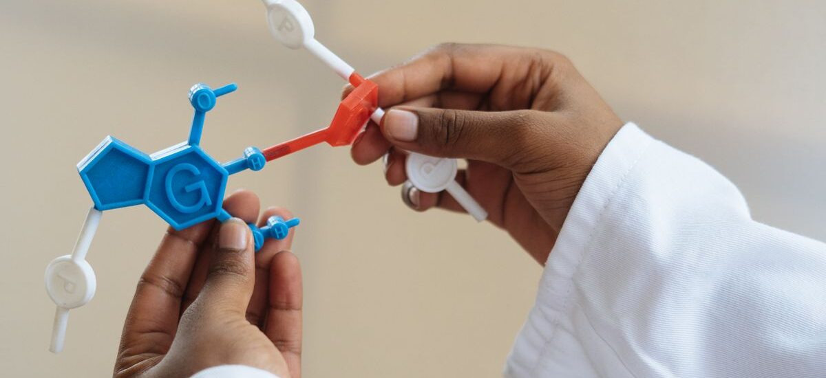 Unrecognizable ethnic scientist wearing lab coat and examining plastic molecule model while standing in laboratory after necessary research
