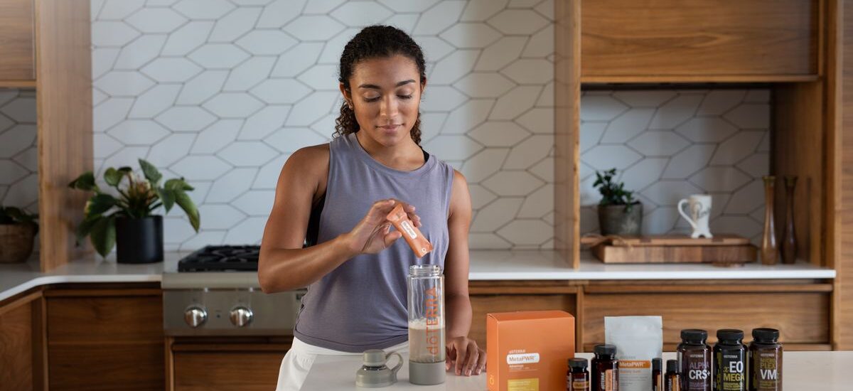 A woman uses essential oils and supplements in a contemporary kitchen for wellness.