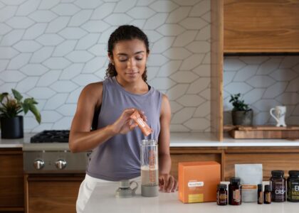 A woman uses essential oils and supplements in a contemporary kitchen for wellness.