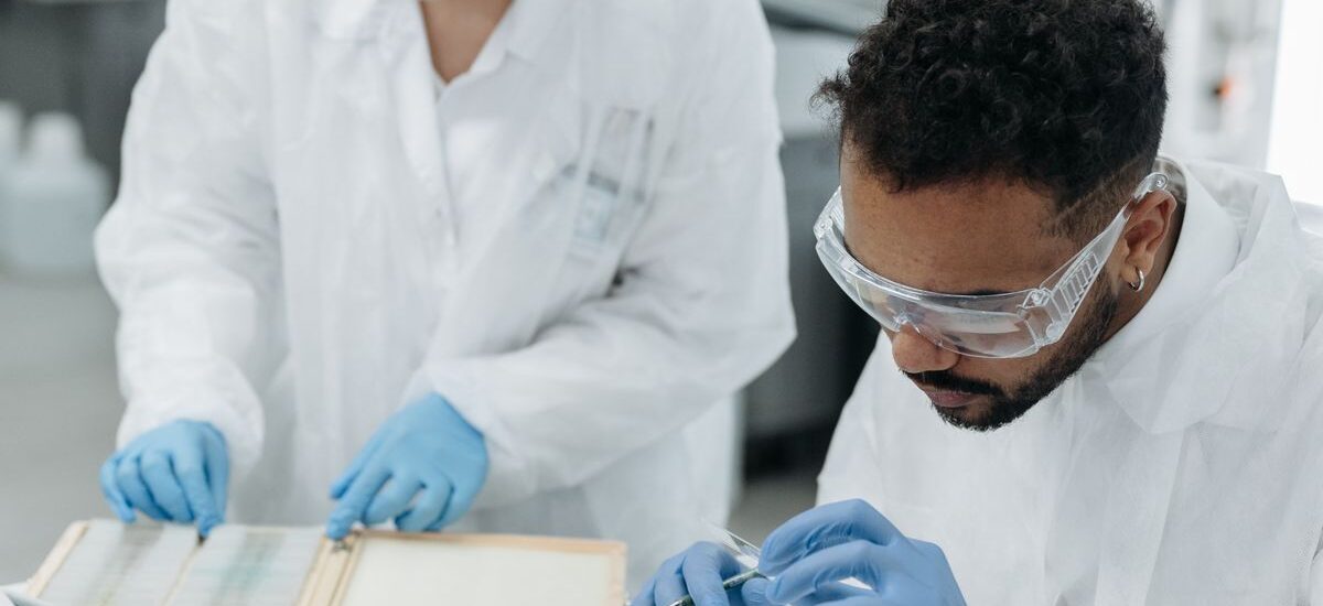 Two scientists in protective gear analyze samples in a modern laboratory setting.