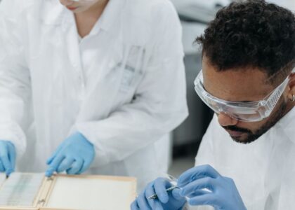 Two scientists in protective gear analyze samples in a modern laboratory setting.